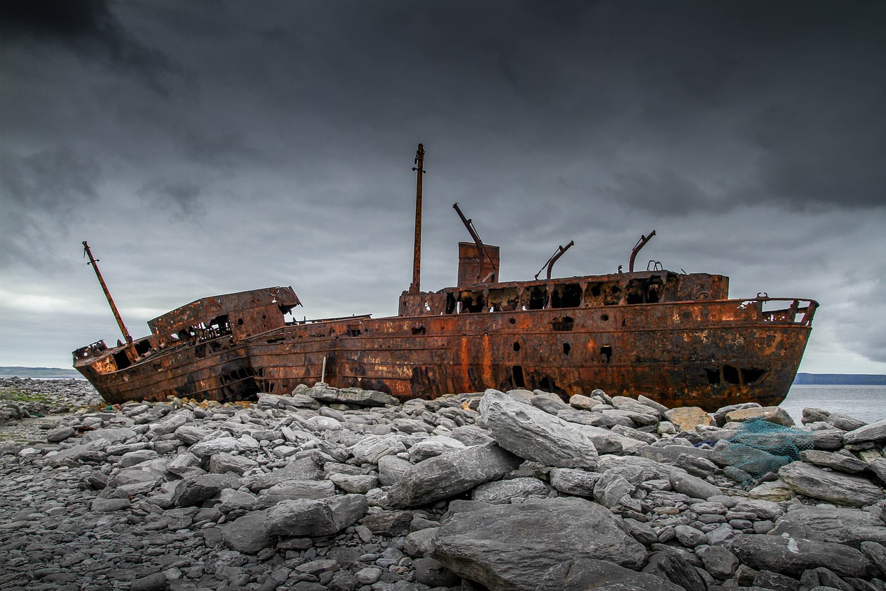 two rusted ships sitting on top of a rocky beach, a portrait, by Edward Corbett, pexels contest winner, destruction around her, with lots of dark grey rocks, full length photo, wide long shot