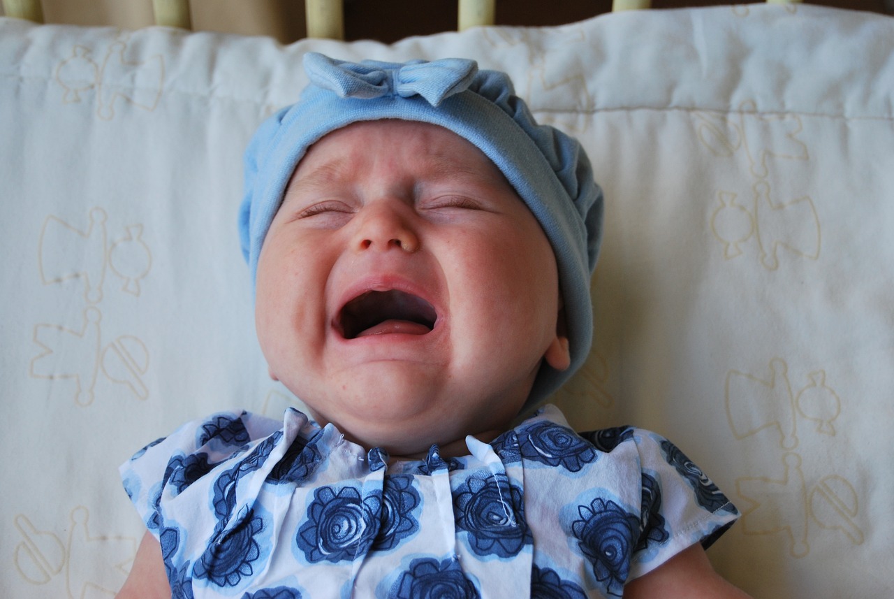 a close up of a baby crying on a bed, a picture, incoherents, a broad shouldered, poppy, bitter, laica chrose