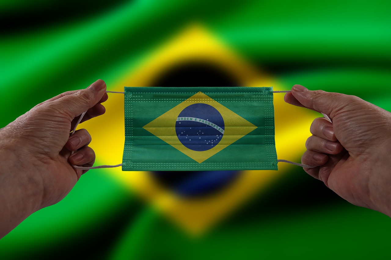 two hands holding a mask in front of a brazilian flag, a photo, medical mask, detailed zoom photo, portlet photo, flags