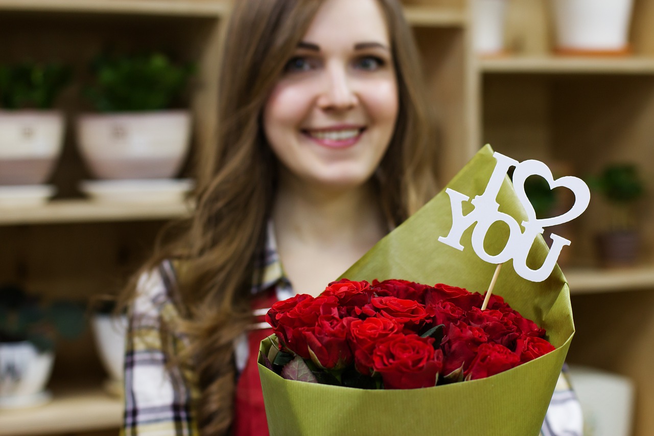 a woman holding a bouquet of red roses, a picture, by Julia Pishtar, shutterstock, flower shop scene, i love you, smiling young woman, close - up photo