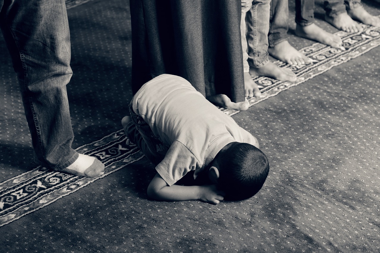 a black and white photo of a young boy kneeling on the floor, a picture, by Sheikh Hamdullah, pexels, hurufiyya, prayer, usa-sep 20, centred, blessed