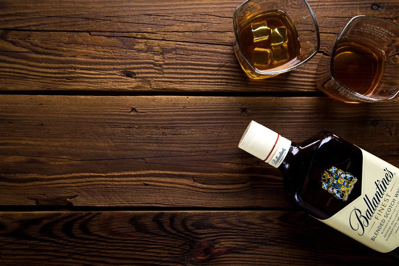 a bottle of whiskey next to a glass of whiskey, pixabay, on a wooden desk, shot from above, banner, istockphoto