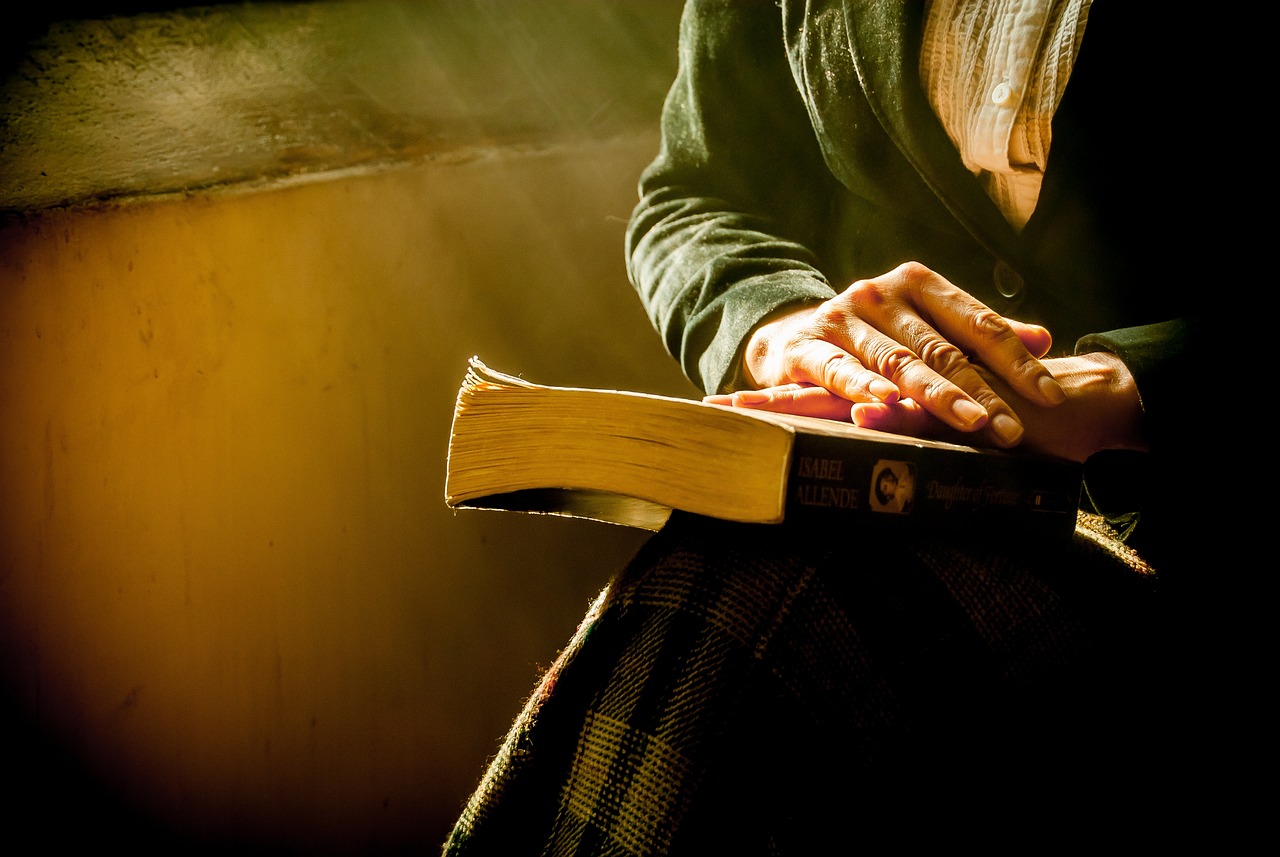 a close up of a person holding a book, by Jason Felix, realism, dramatic golden light, grungy woman, tibetan book of the dead, sitting down