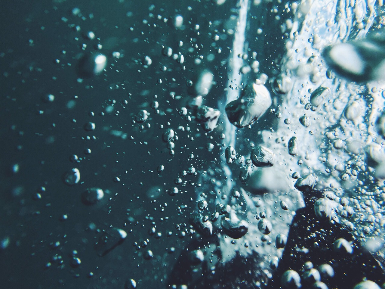 a close up of a body of water with bubbles, pexels, happening, underwater looking up, droplets on the walls, washed out background, detailed cinematic photography