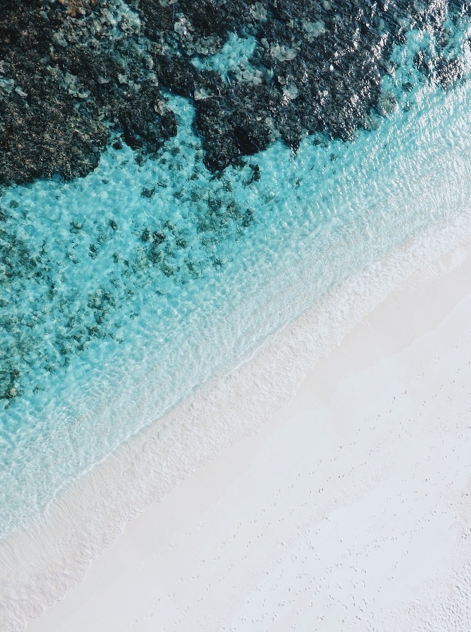 a person riding a surfboard on top of a sandy beach, unsplash contest winner, minimalism, coral reefs, view from helicopter, maldives in background, micro detail 4k