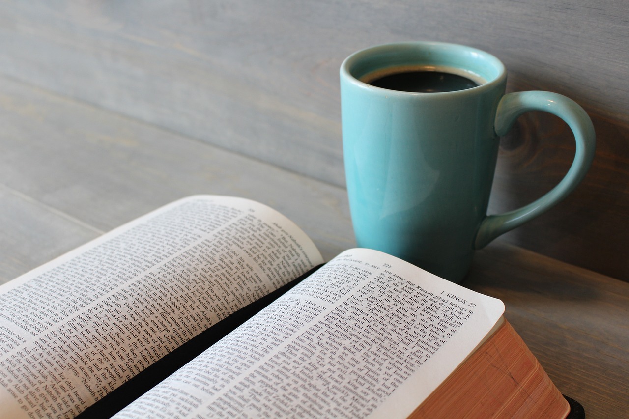 a cup of coffee and an open book on a table, biblical, blue, high res photo