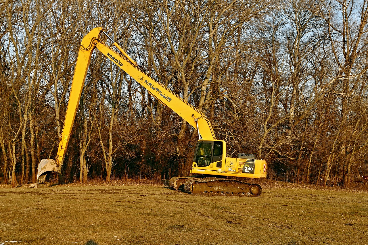 a large yellow excavator sitting on top of a lush green field, illinois, kelogsloops and greg rutkowski, long arms, ground broken