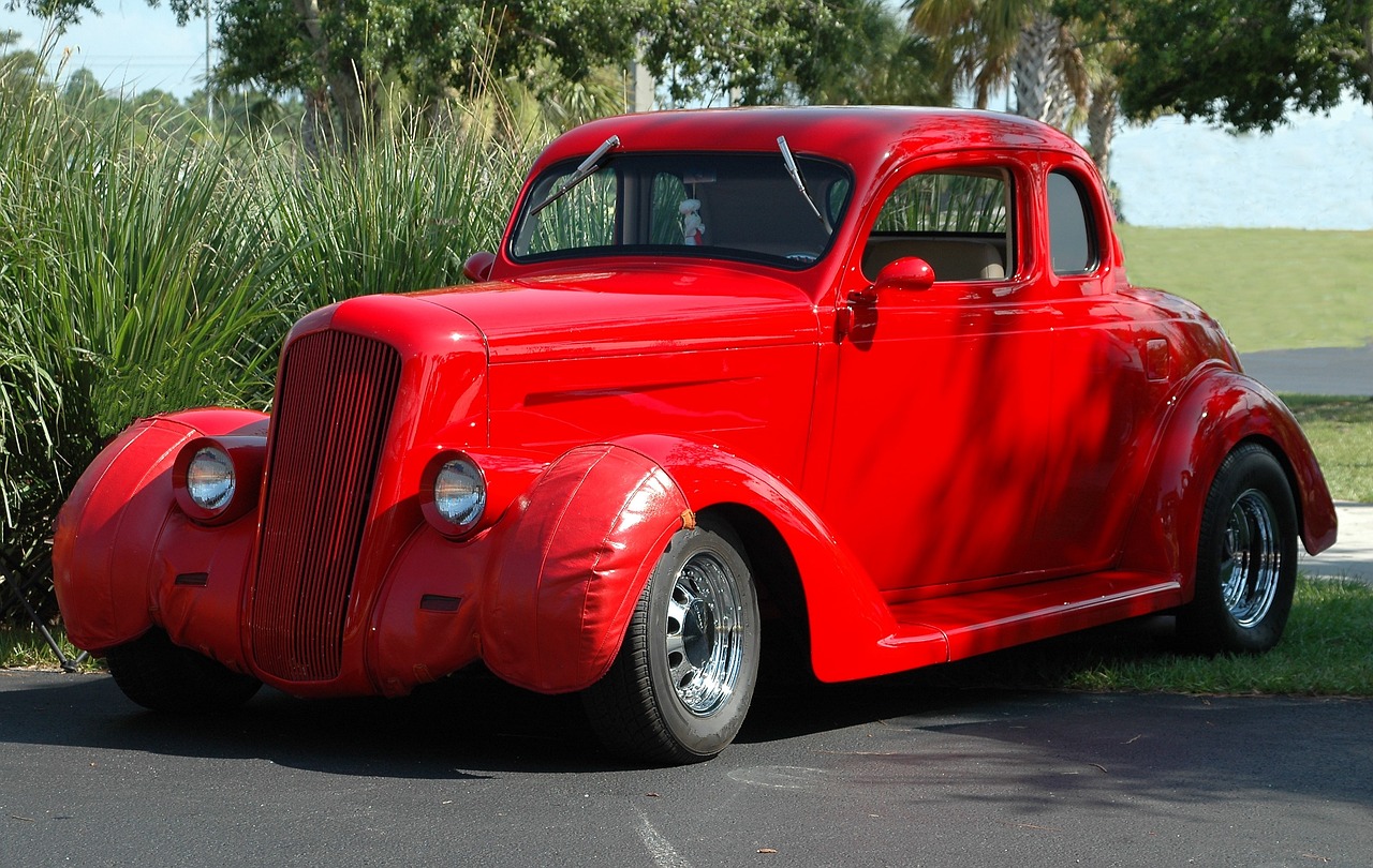 a red classic car parked in a parking lot, by Dave Melvin, 1936, professional paint job, long front end, sun coast