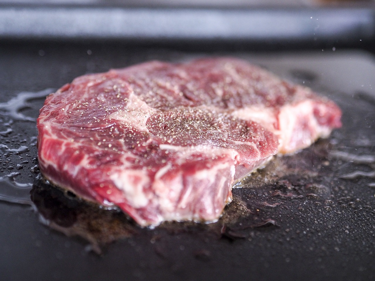 a close up of a piece of meat on a grill, flattened, food blog photo, close-up shot taken from behind, steak