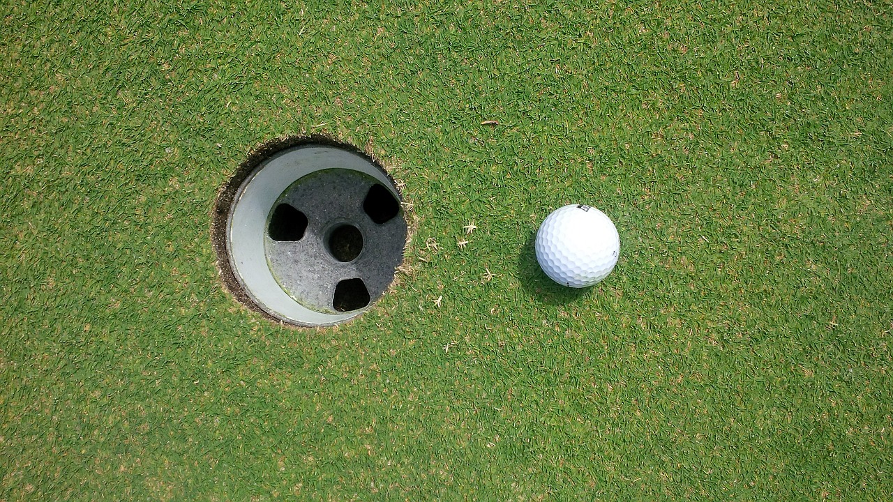 a close up of a golf ball near a hole, by David Simpson, precisionism, wikimedia, high-angle, huge black round hole, rectangle