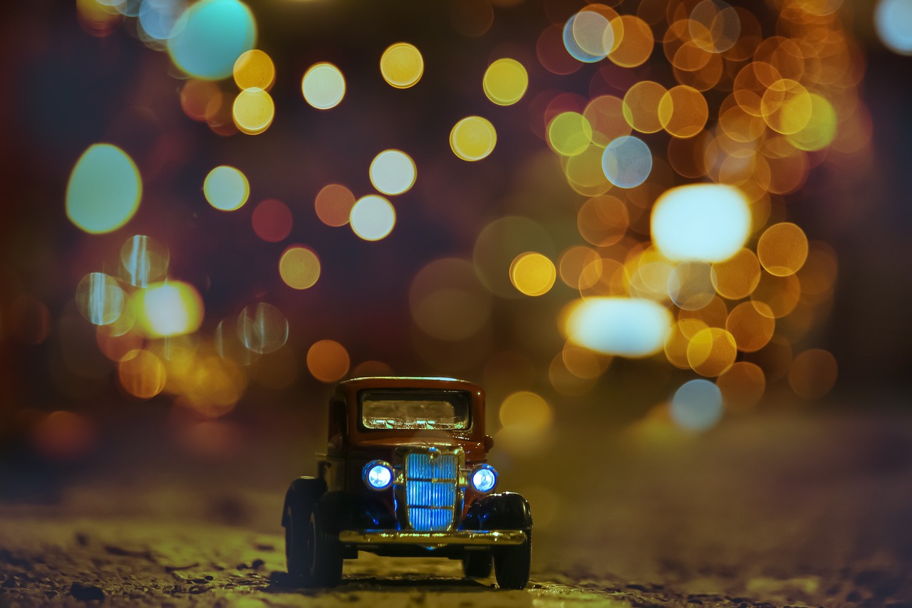 a toy car that is sitting in the sand, a tilt shift photo, city lights bokeh, old timey, night photo, bokeh photo