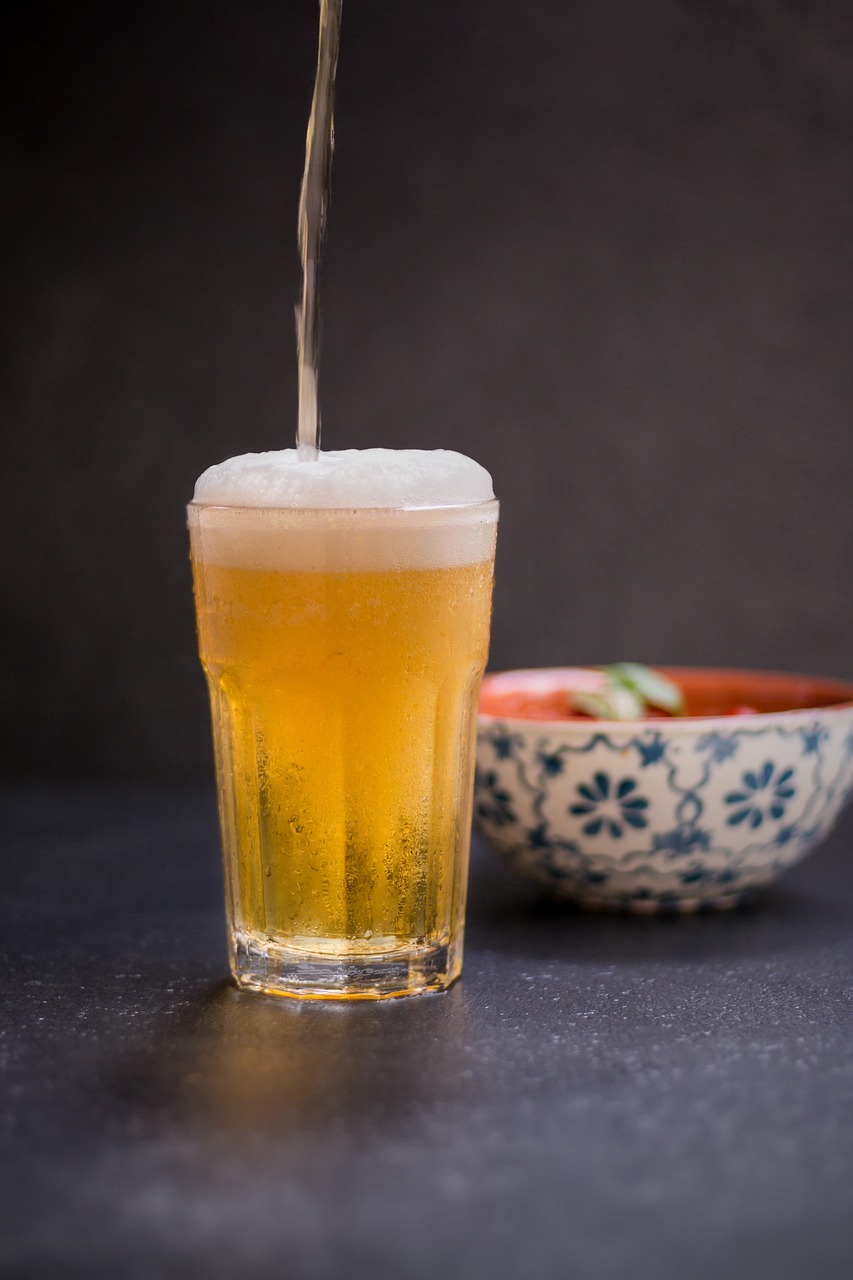 a glass of beer next to a bowl of food, a stock photo, inspired by Kanō Shōsenin, shutterstock, shin hanga, pouring, high res, mid shot portrait, bangalore