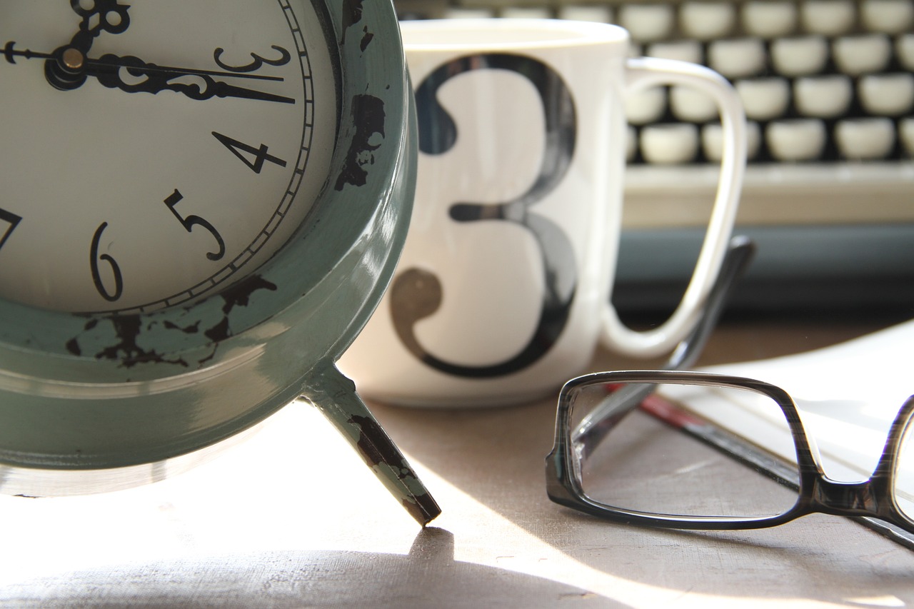 a clock sitting on top of a table next to a pair of glasses, a photo, happening, high res photo
