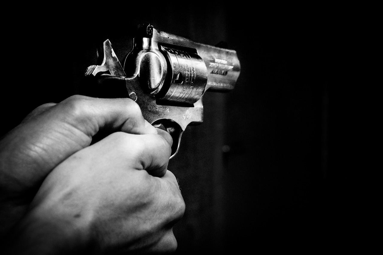 a person holding a gun in their hand, a black and white photo, by Mirko Rački, pixabay, realism, with violence, revolver, stock photo, close - up photo