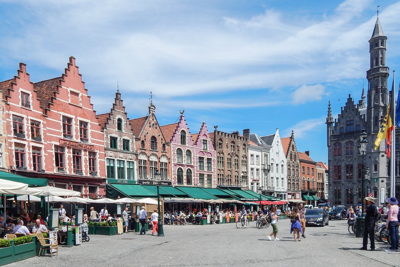 a group of people walking down a street next to tall buildings, by Justus van Gent, pexels, renaissance, white buildings with red roofs, flanders, market square, bright summer day