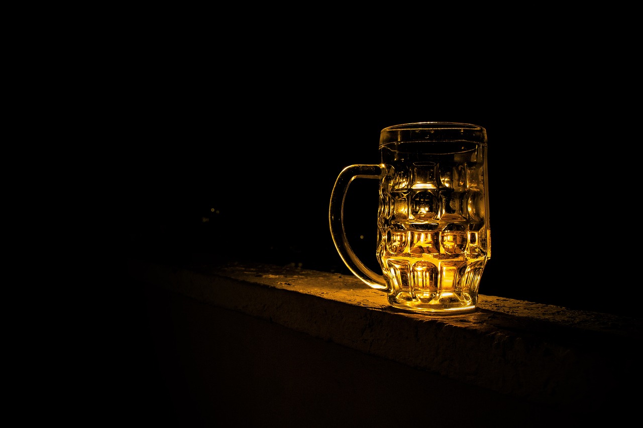 a glass of beer sitting on a ledge, a tilt shift photo, in an alley at night back lit, high res photo, “ golden cup, very detailed photo