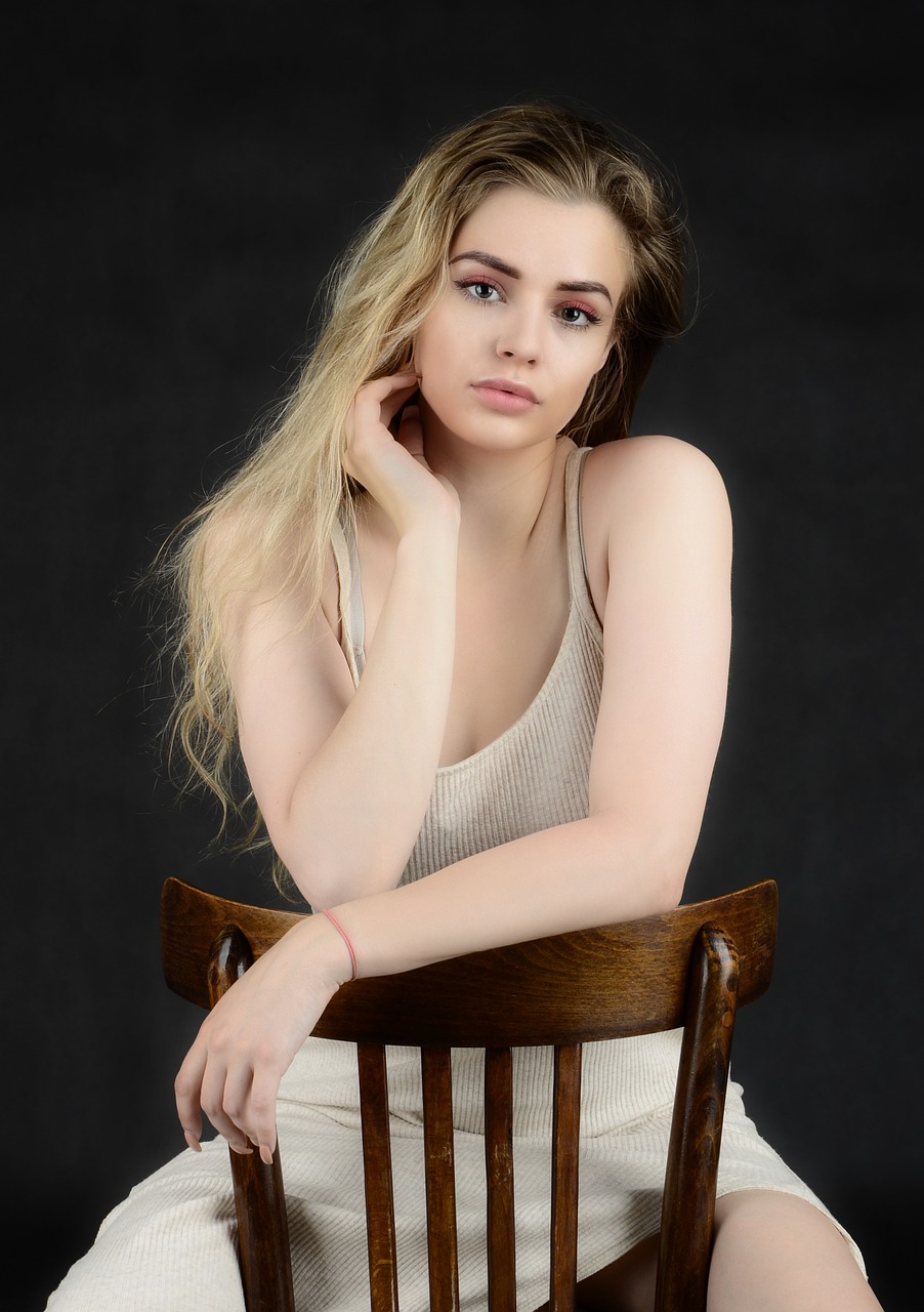 a woman sitting on top of a wooden chair, a portrait, inspired by Harry Morley, shutterstock, gorgeous young model, wearing a camisole, ellie victoria gale, head and shoulder shot