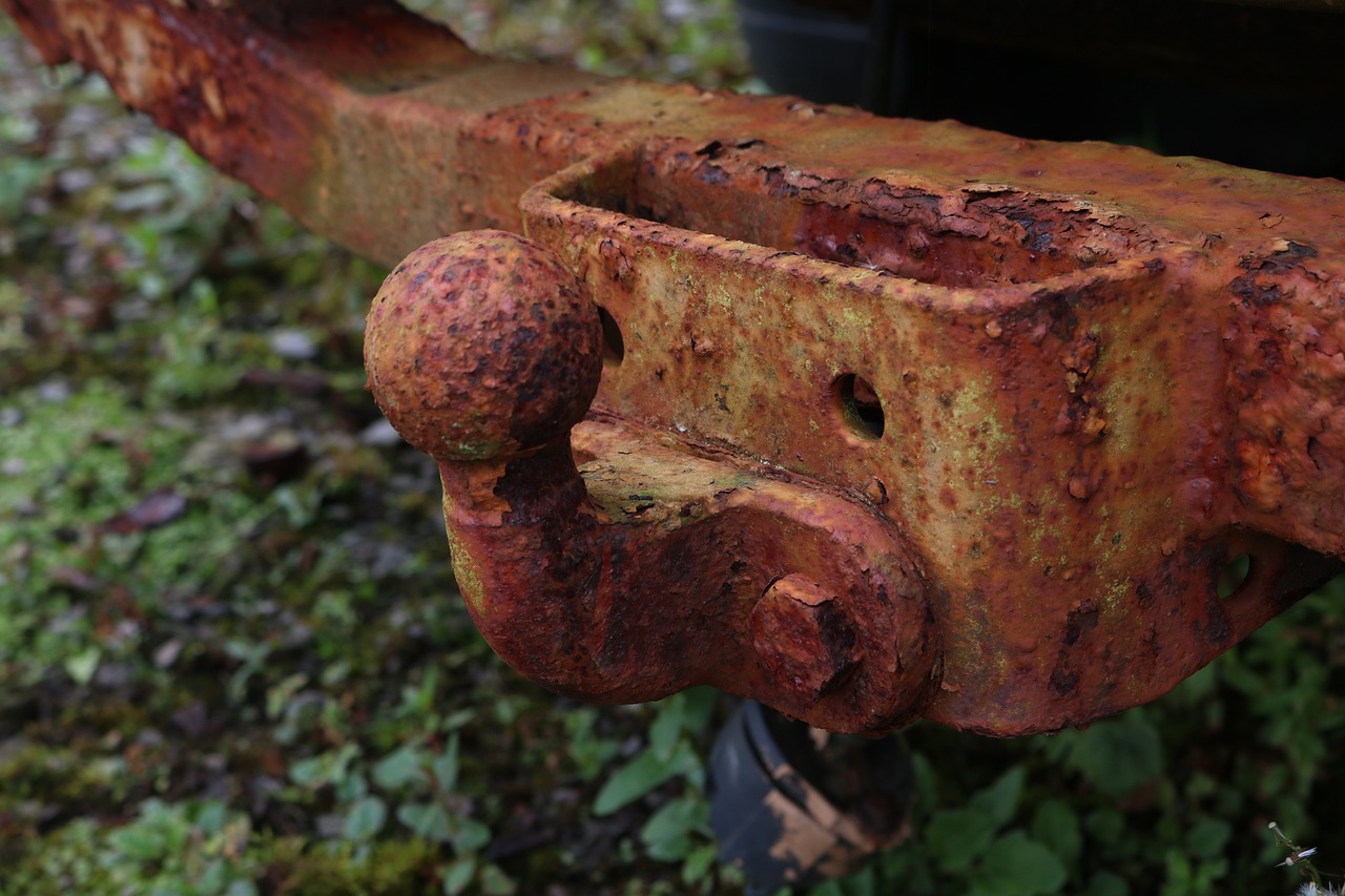 an old rusted piece of machinery sitting in the grass, by Richard Carline, hoog detail, trailer, bottom body close up, ornamental rober