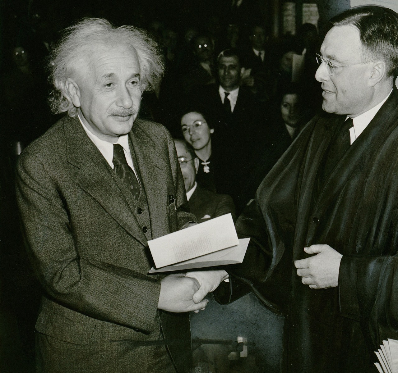 a couple of men standing next to each other, albert einstein, wearing an academic gown, benjamin vnuk, shaking hands