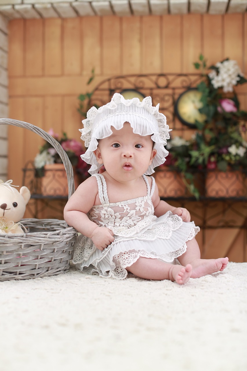 a baby sitting next to a basket with a teddy bear, by Bernardino Mei, pixabay contest winner, wearing a white sundress, girl with a birdcage on her head, portrait shot 8 k, wan adorable korean face