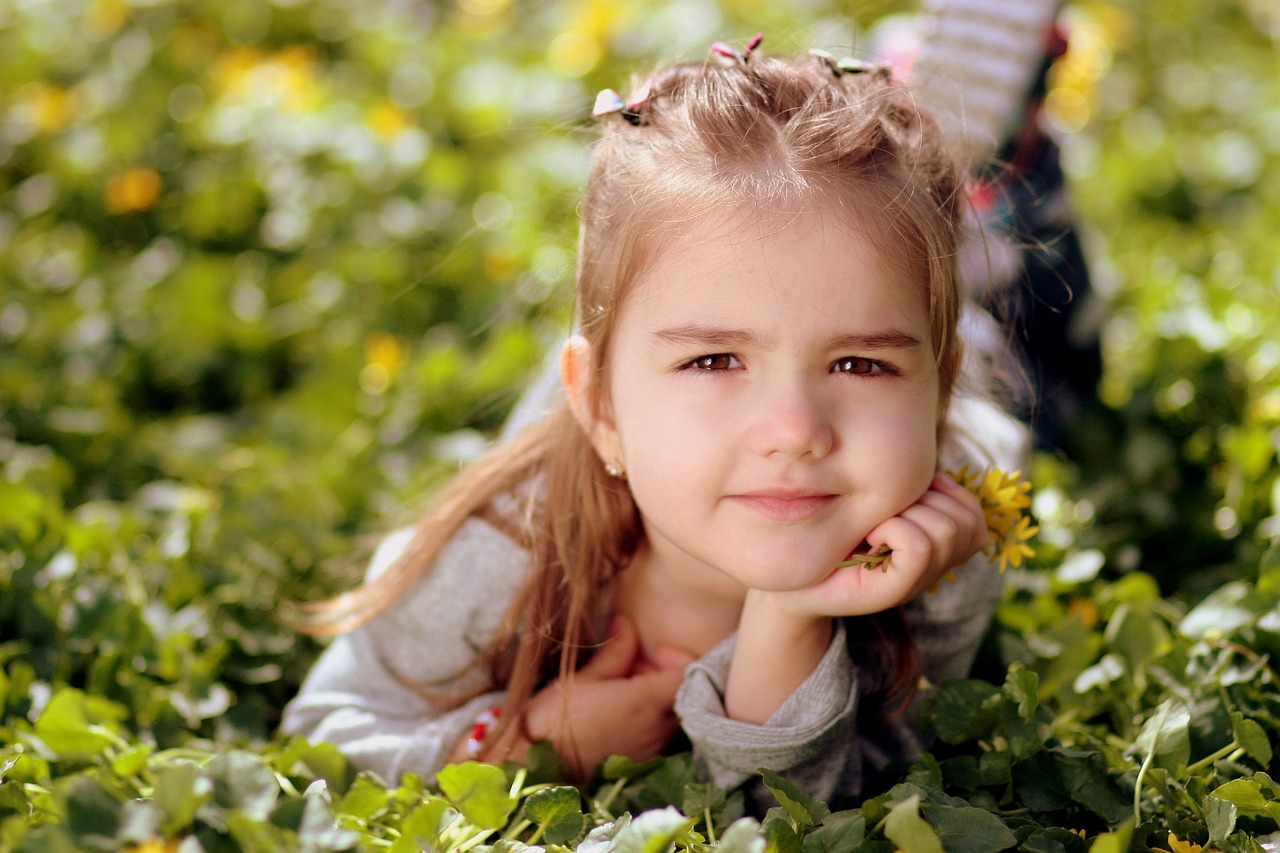 a little girl laying on top of a lush green field, a picture, realism, cute faces, avatar image, close up photography, small