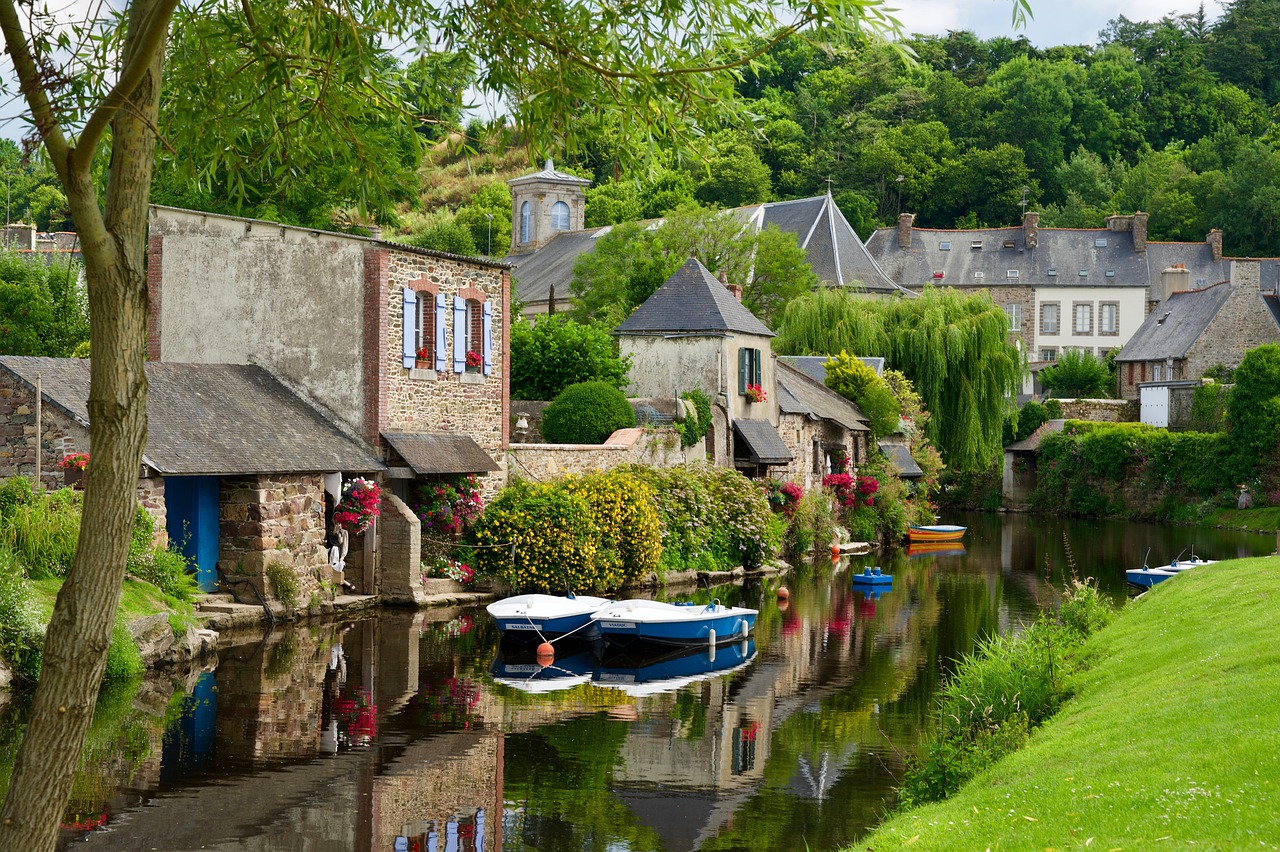 a group of boats sitting on top of a river next to a lush green hillside, a picture, by Bernard D’Andrea, shutterstock, french village interior, cornwall, bocage, stock photo