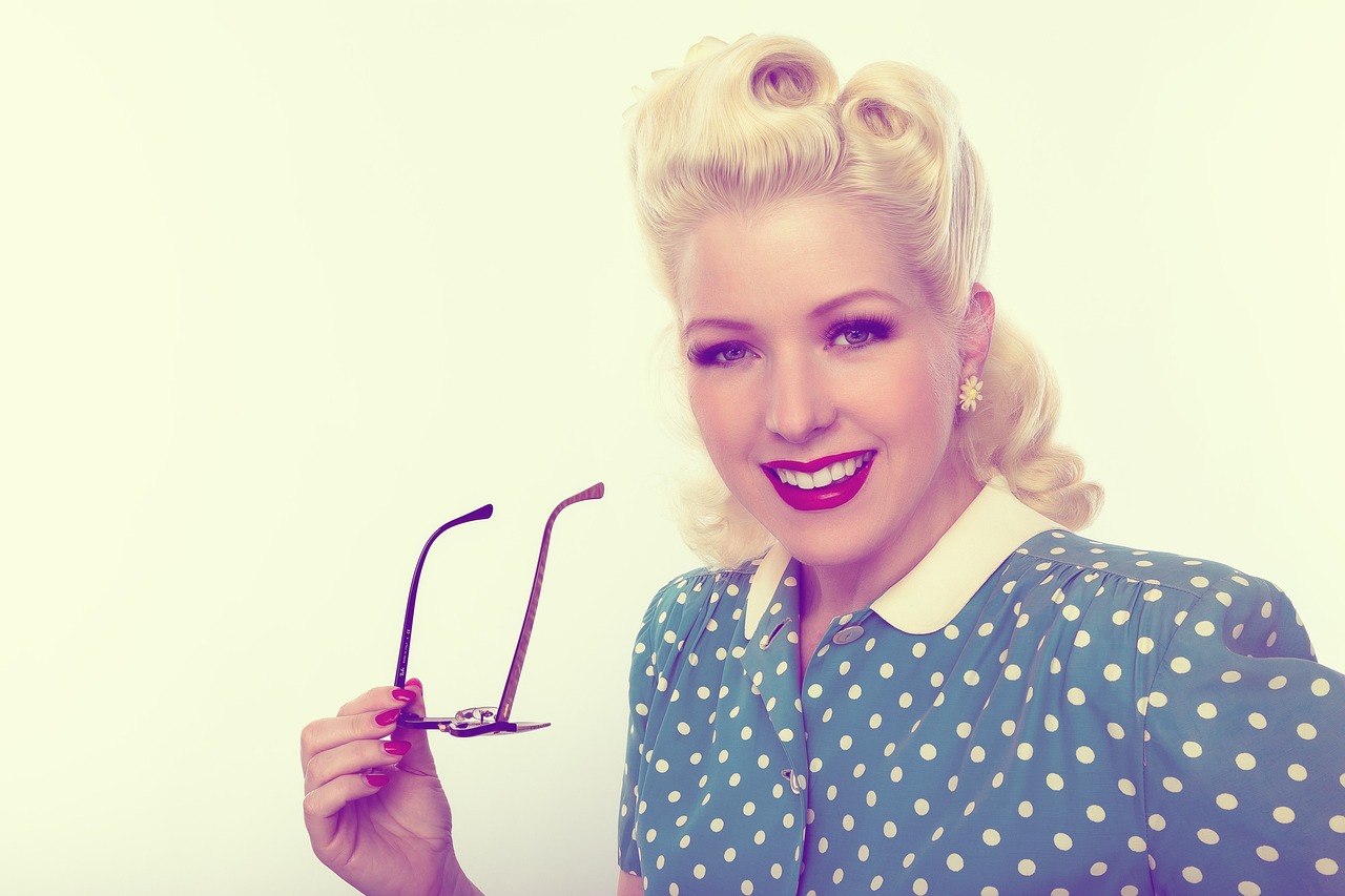 a woman holding up a pair of glasses, by Dan Luvisi, tumblr, 50s style infomercial, polkadots, piercing, a girl with blonde hair