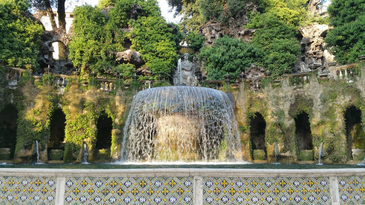 a man sitting on a bench in front of a fountain, a mosaic, inspired by Serafino De Tivoli, pixabay, with trees and waterfalls, palace of the chalice, vincenzo riccardi, gui guimaraes