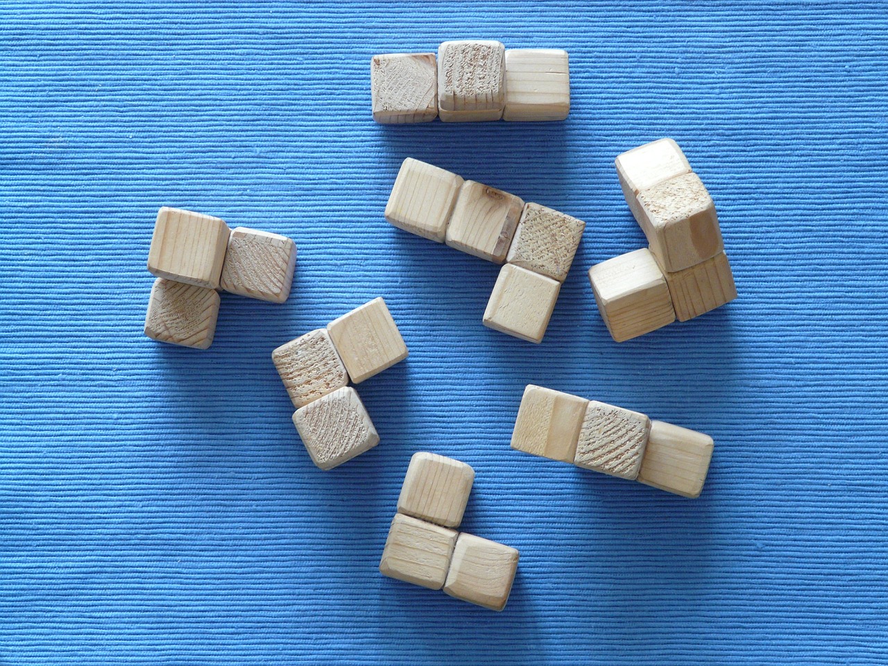 a group of wooden blocks sitting on top of a blue surface, a jigsaw puzzle, inspired by Isamu Noguchi, flickr, op art, dices map book miniatures, pine wood, 3/4 view from below, cross hatched