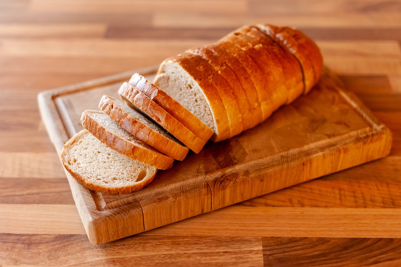 a loaf of bread sitting on top of a cutting board, by Franz Hegi, shutterstock, sliced bread in slots, high detail product photo