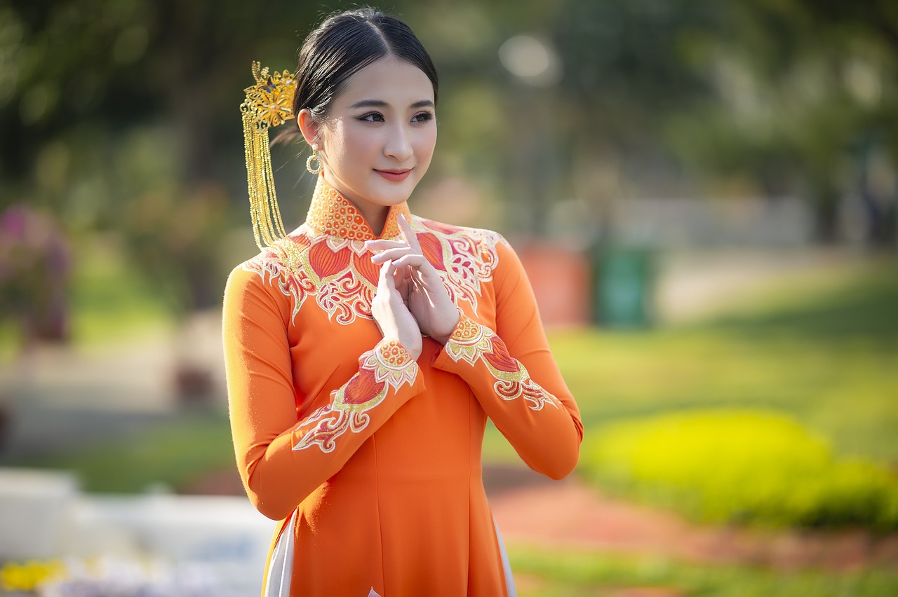 a woman in an orange dress poses for a picture, by Bernardino Mei, shutterstock, vietnamese temple scene, portrait of a young empress, greeting hand on head, stock photo