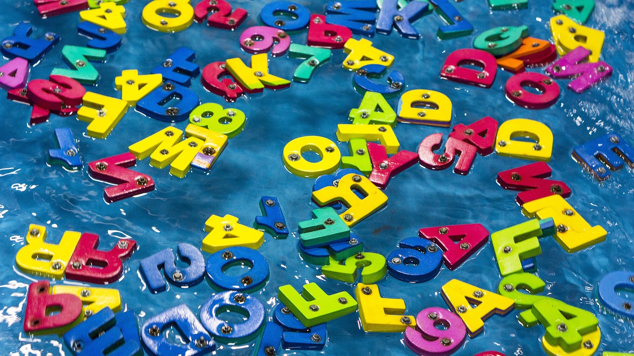 a table topped with lots of colorful plastic letters, by Aleksander Gierymski, flickr, closeup fantasy with water magic, aquatic devices, magnetic, closeup!!