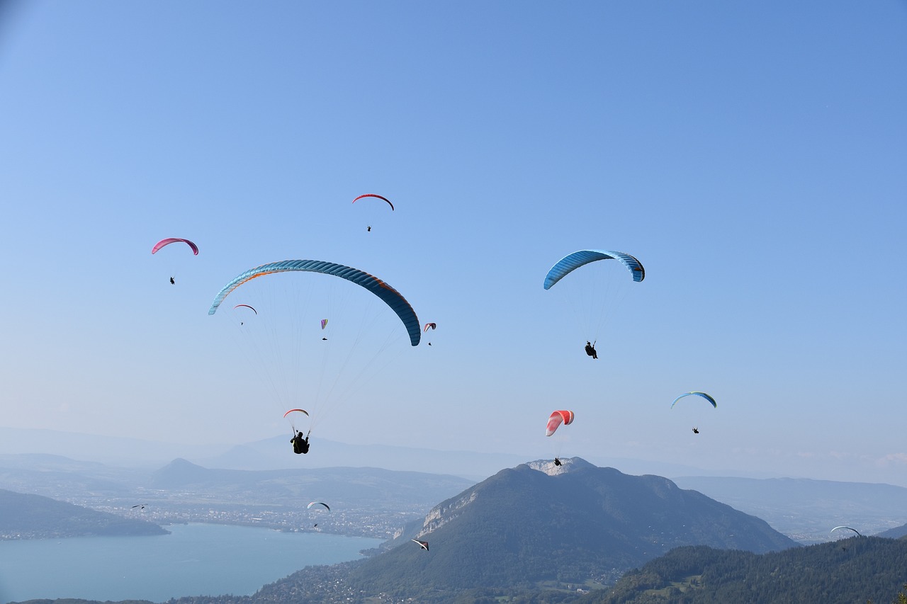 a group of people flying kites on top of a mountain, a picture, by Niko Henrichon, shutterstock, skydiving, france, view from the side”, gondolas