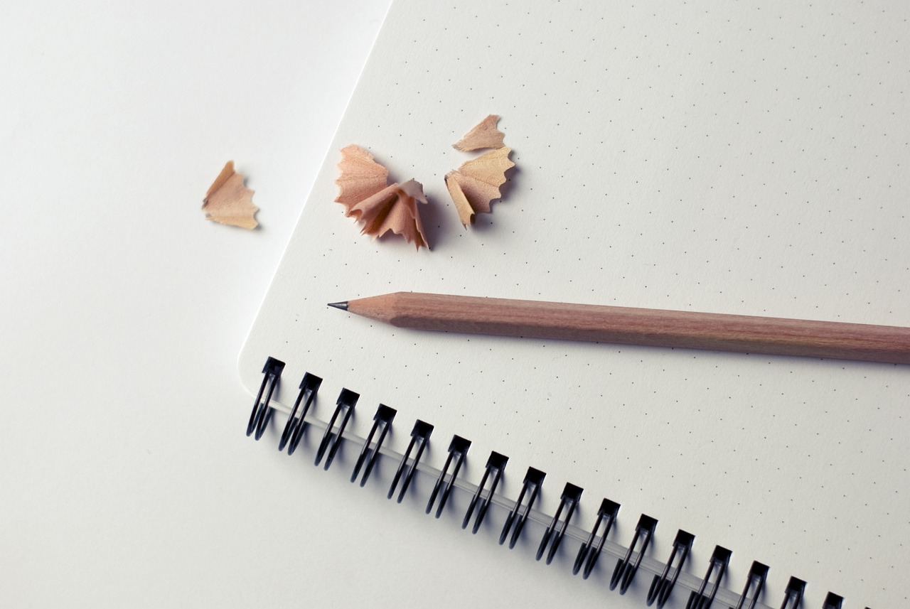 a pencil sitting on top of a notebook next to a pencil sharper, a drawing, minimalism, shattering expectations, clean photo, product introduction photo