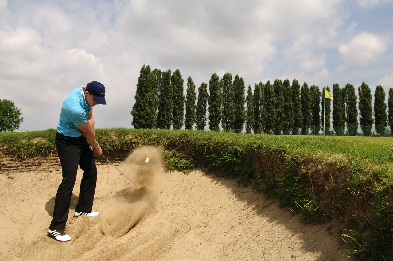 a man in blue shirt playing a game of golf, by Werner Gutzeit, flickr, sand piled in corners, belgium, sand storm, planted charge