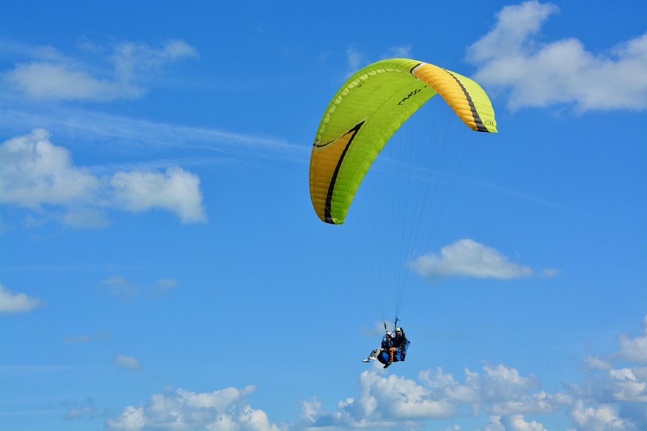 a person that is in the air with a parachute, a photo, green and yellow colors, azure blue sky, florida, closeup photo