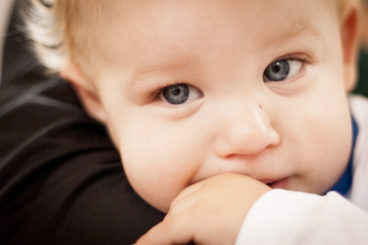 a close up of a person holding a baby, serious business, with blue eyes, hand over mouth, looking at you