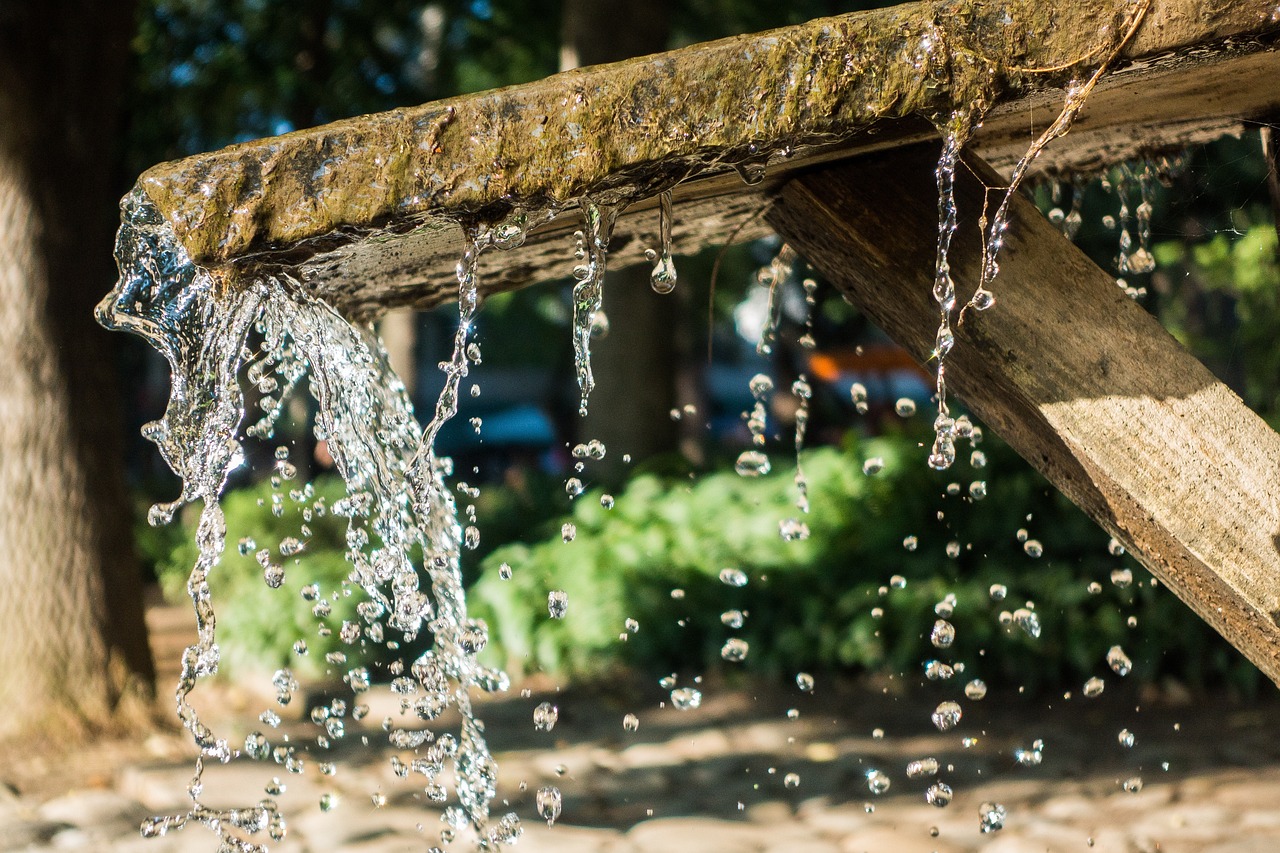 a wooden structure with water coming out of it, a picture, by Niko Henrichon, shutterstock, fountain of water, sunny summer day, bottom shot, drops are falling from above