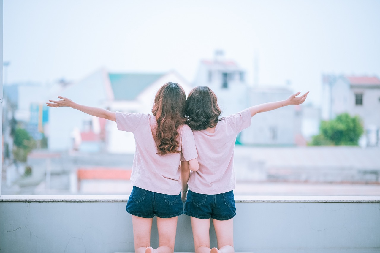 a couple of young girls standing next to each other, a picture, by Tan Ting-pho, shutterstock, aestheticism, from the roof, pink shirt, back pose, half body photo