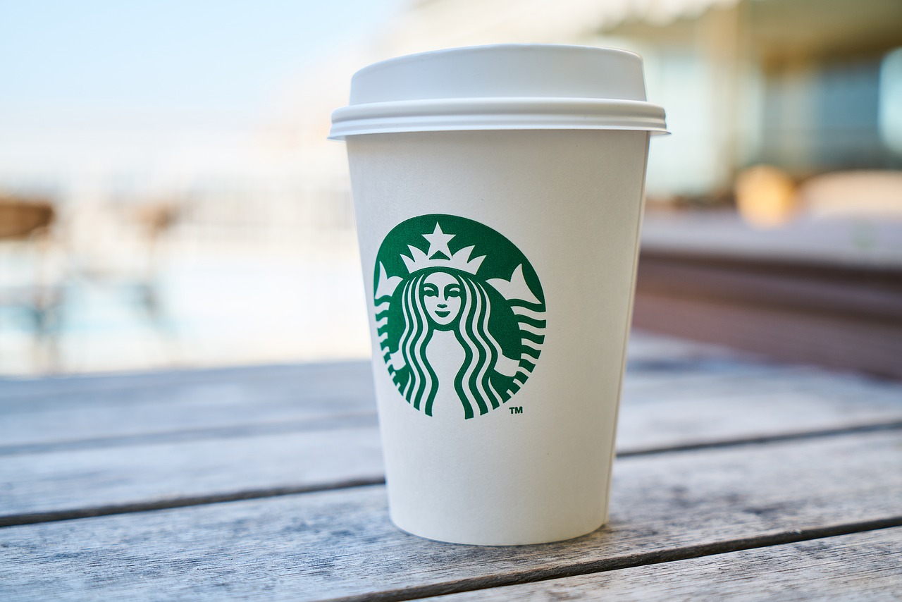 a starbucks cup sitting on top of a wooden table, by Judith Gutierrez, shutterstock, clean and simple design, highly detailed product photo, 🦩🪐🐞👩🏻🦳, al fresco