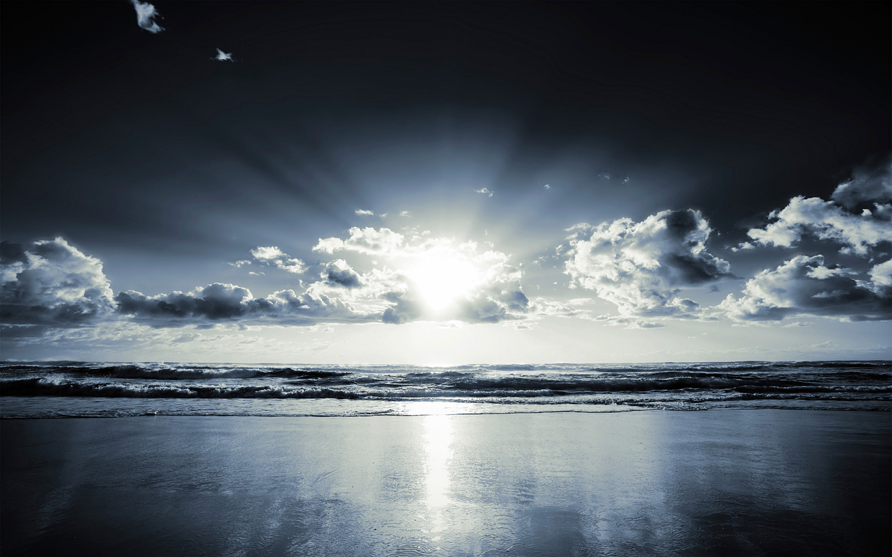 a black and white photo of the sun over the ocean, shutterstock, glossy reflections, blue sunset, black sand, sunrays between clouds