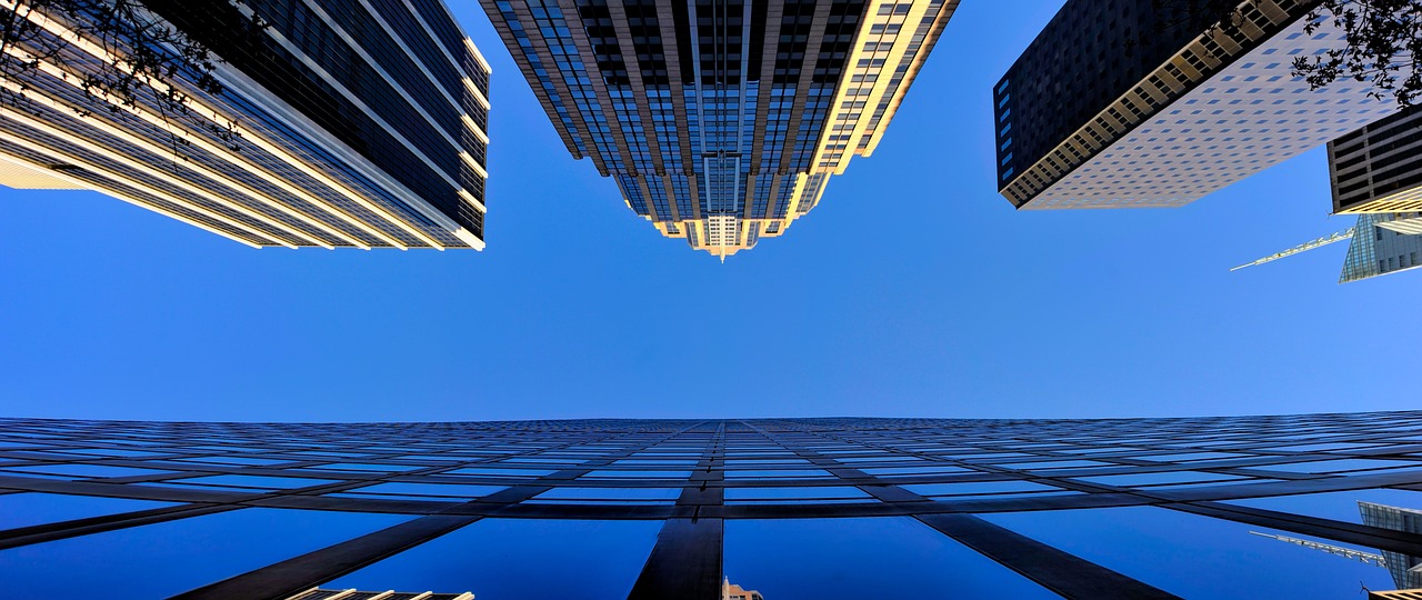 a group of skyscrapers with a blue sky in the background, a picture, by Jan Rustem, minimalism, golden cityscape, wideangle, manhattan, three - point perspective