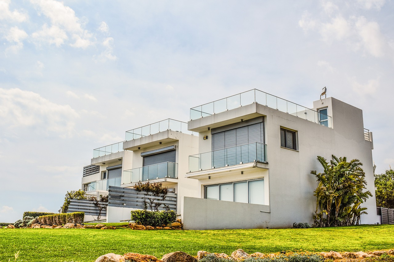 a white house sitting on top of a lush green hillside, by Zahari Zograf, shutterstock, modernism, glass houses, white travertine terraces, apartment, twins