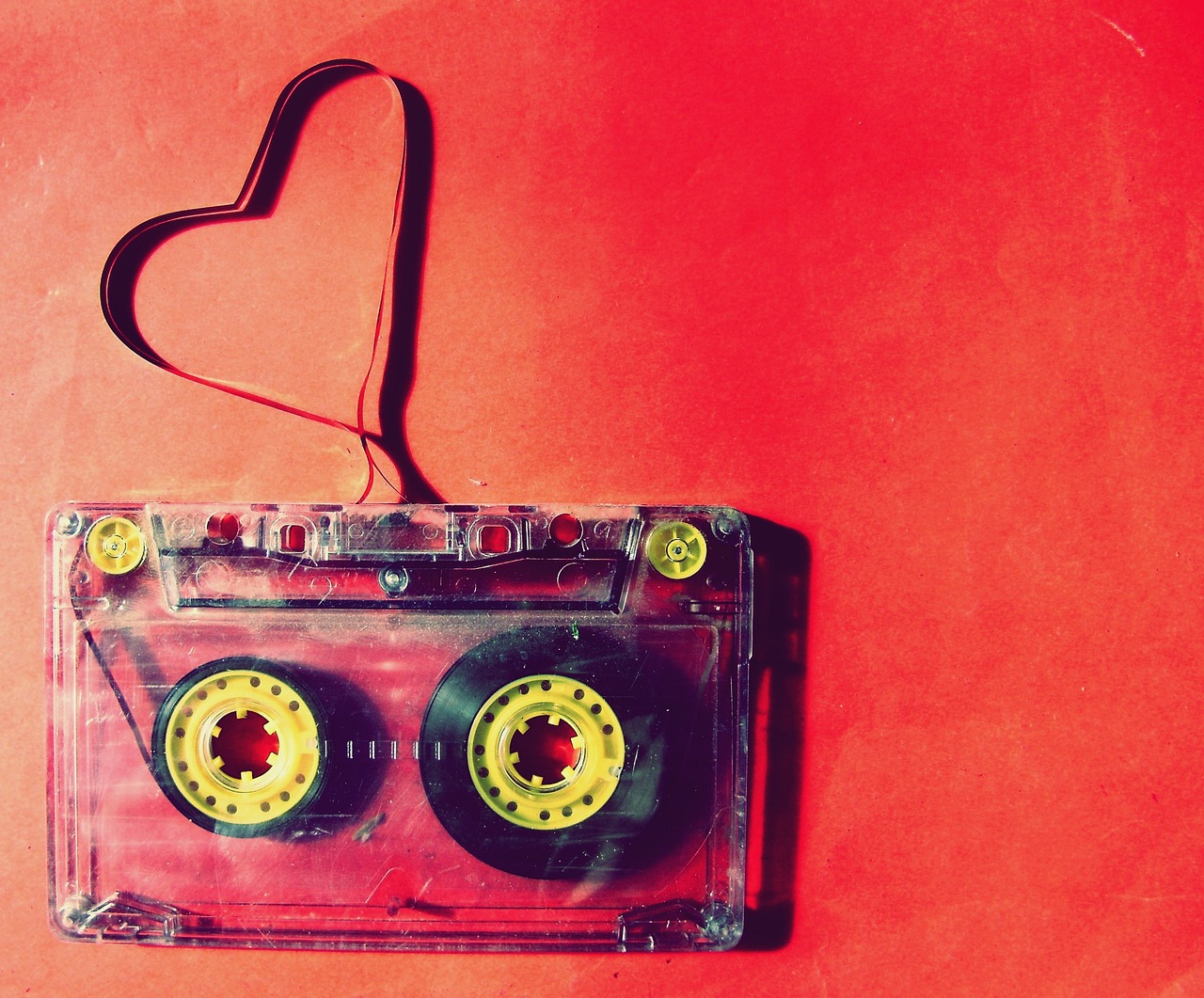 a close up of a cassette on a red surface, romanticism, amazing wallpaper, heart, yellow and red, various artists