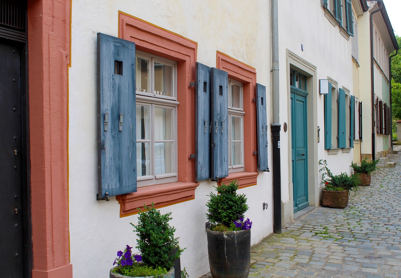 a couple of planters that are on the side of a building, a photo, by Karl Hofer, shutterstock, quaint village, window open, germany. wide shot, blue and orange
