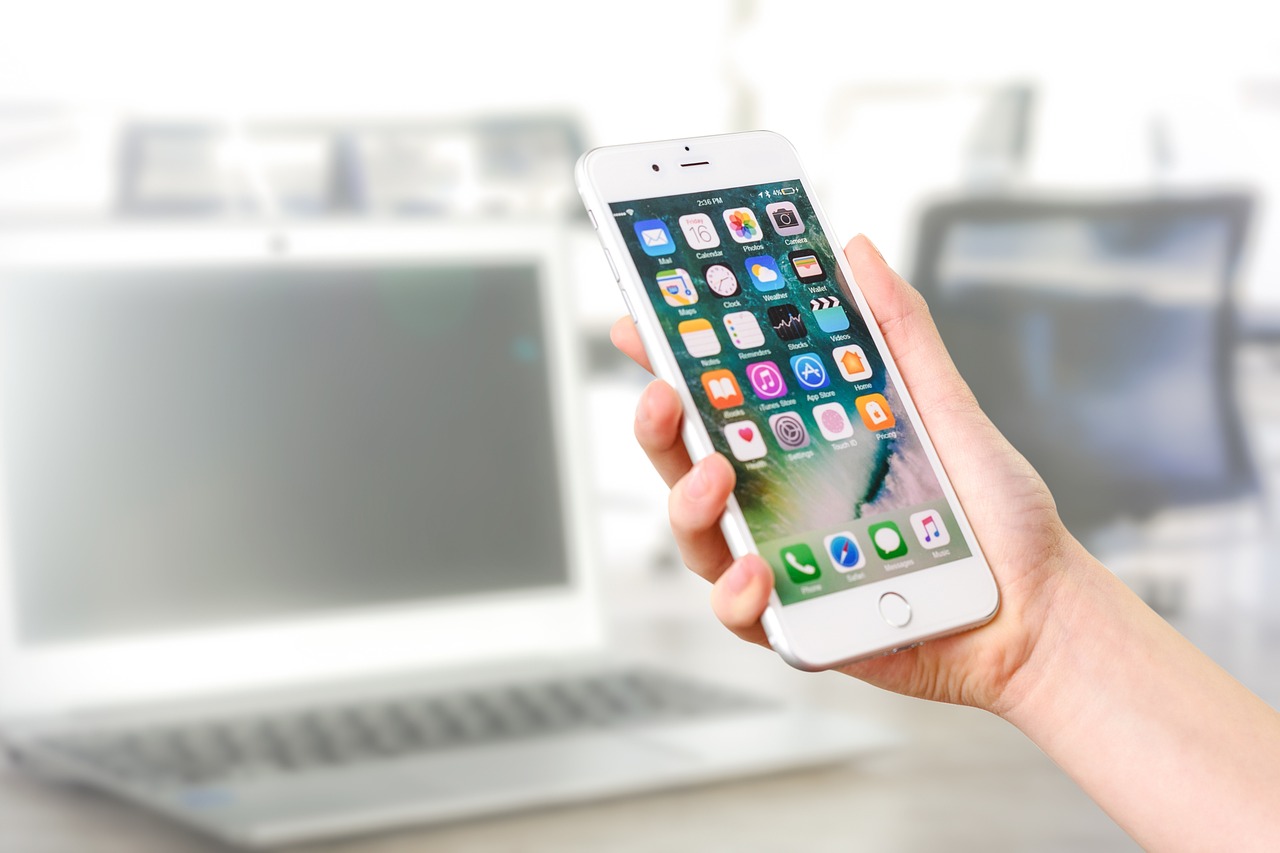 a person holding an iphone in front of a laptop, shutterstock, blurred detail, ios app icon, stock photo