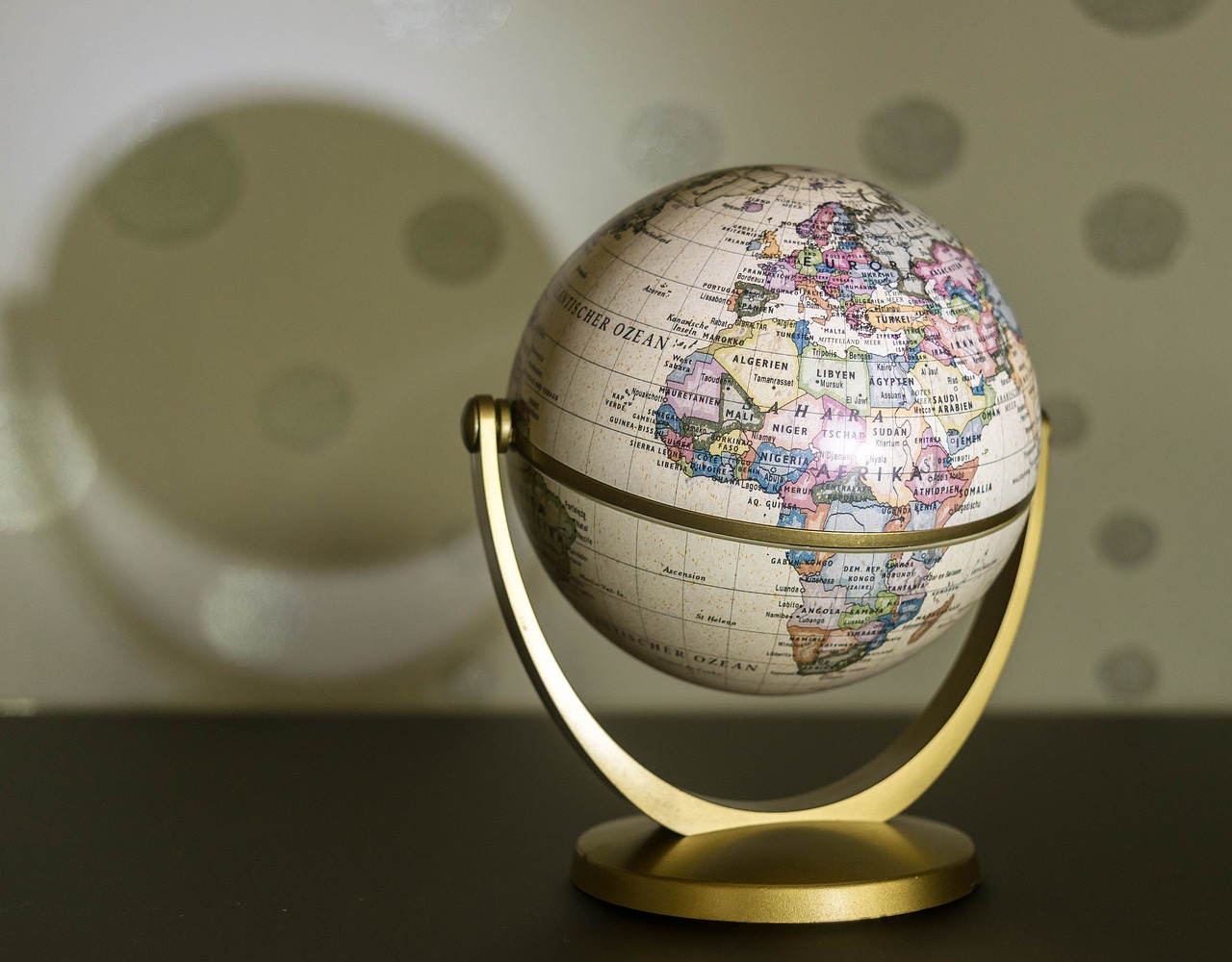a small globe sitting on top of a table, a picture, excessivism, ivory, wallpaper background, slightly blurred, circular