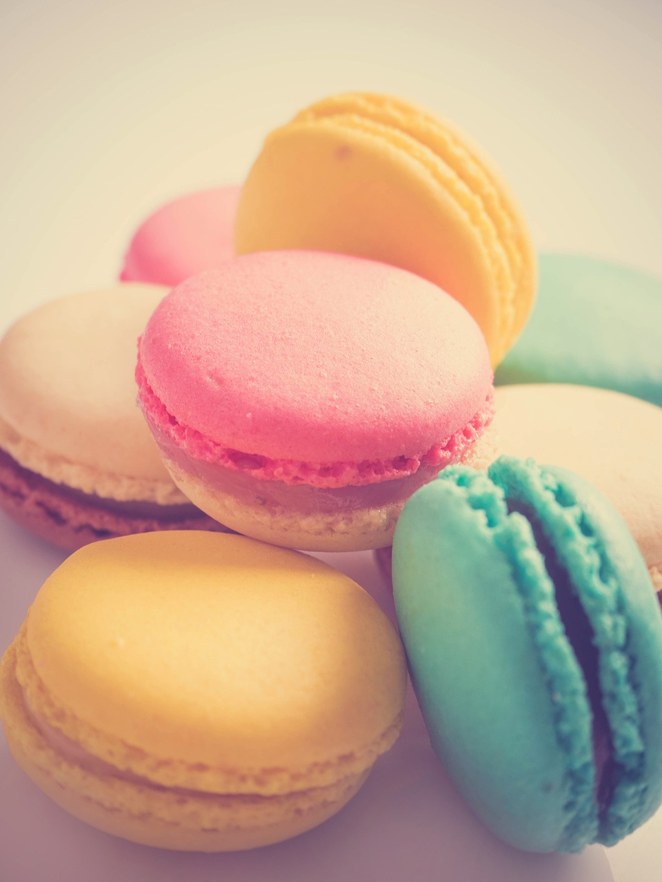 a pile of macarons sitting on top of a white plate, a pastel, romanticism, vintage saturation, 33mm photo