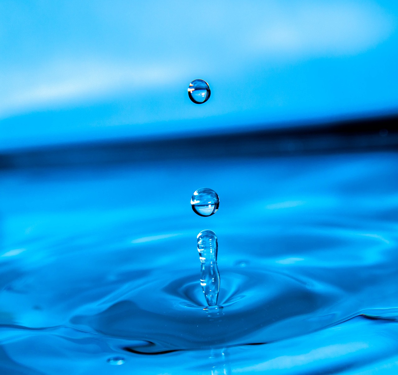 a drop of water falling into a blue pool, a macro photograph, shutterstock, hyper detailed background, stock photo