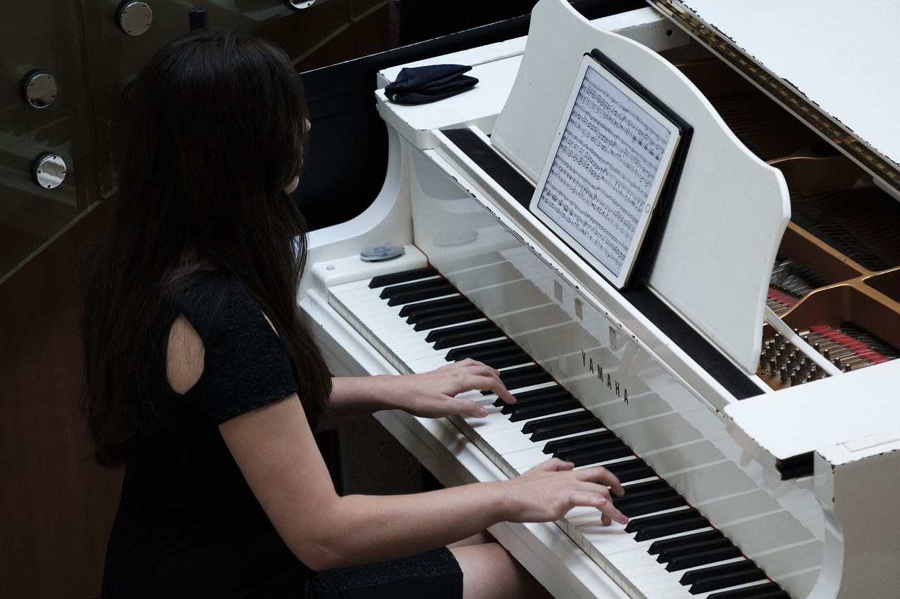 a woman in a black dress playing a white piano, shutterstock, photo taken in 2018, student, performance, half - length photo